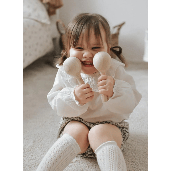 child playing with Maracas made with FSC certified oak wood. All  instruments by Love Note Co are handmade items, non-toxic, eco-friendly and sustainably sourced. Stocked at LOVINLIFE Co Byron Bay for all your gifts, candles and interior decorating needs