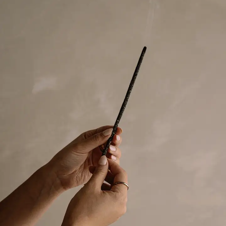 Cedar and Myrrh Black Copal Hand Rolled Incense Stick - smoking being held by two hands - Stocked at LOVINLIFE Co Byron Bay for all your gifts, candles and interior decorating needs