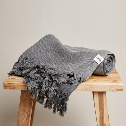 Saarde's Vintage Wash 100% OEKO-TEX® Turkish Cotton Throw Blanket in Charcoal – Pictured rolled up, resting on small wooden stool - available at LOVINLIFE Co Byron Bay for all your gifts, candles and interior decorating needs