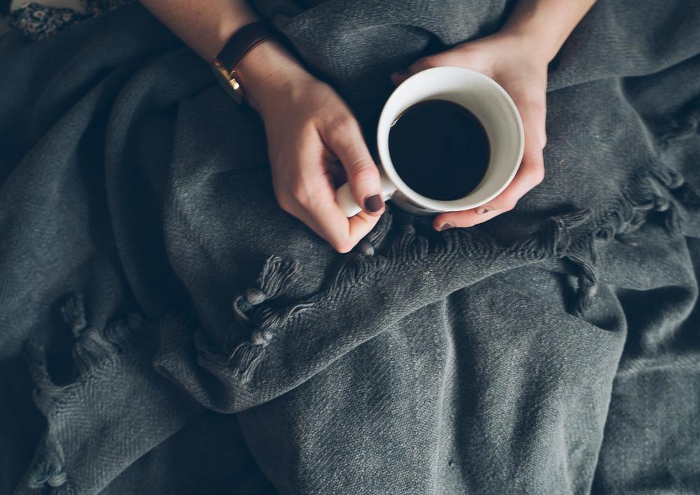 Saarde's Vintage Wash 100% OEKO-TEX® Turkish Cotton Throw Blanket in Charcoal – Pictured from above on the lap of a person holding a hot drink - available at LOVINLIFE Co Byron Bay for all your gifts, candles and interior decorating needs