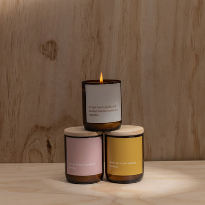 Commonfolk Candles from the heartfelt collection - amber glass jar with wood lids, stacked on wooden backdrop with top candle lit - Stocked at LOVINLIFE Co Byron Bay for all your gifts, candles and interior decorating needs